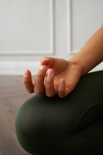 Close-up of hands gently folded in the lap during a seated meditation, with soft, diffused light highlighting the hands.