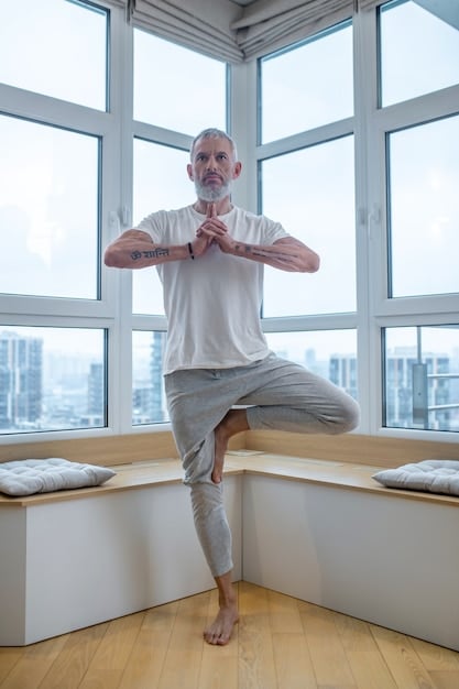 An older man practices yoga in a calm and airy room. The man is centered in the image.