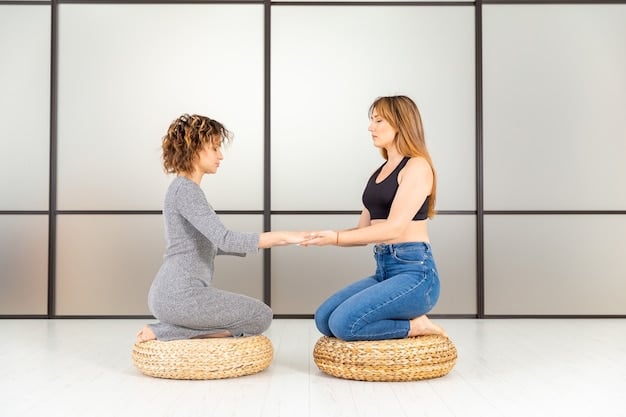 A yoga instructor demonstrating proper alignment in a modified Warrior II pose, using a chair for support and demonstrating correct form for a student with limited mobility.
