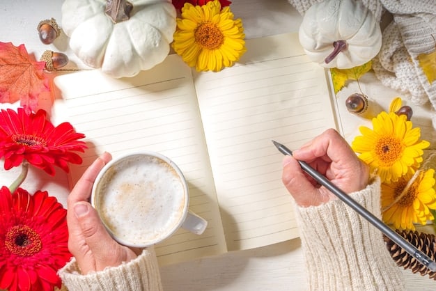 A hand writing in a gratitude journal in a brightly lit room, with a cup of tea and a small vase of flowers on the table.