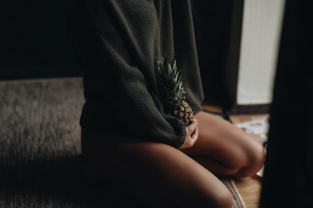 A close-up shot of a pregnant woman's hands gently resting on her belly while sitting in a comfortable cross-legged position during a yoga session.