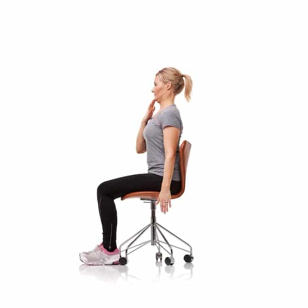 A person demonstrating the seated spinal twist pose in an office chair, with their torso twisted to the side, one hand on the knee and the other on the back of the chair.