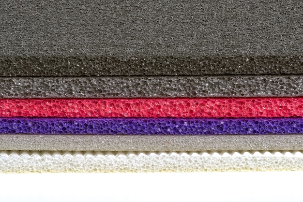 A side-by-side comparison of different yoga mat materials: PVC (shiny and smooth), TPE (textured and colorful), Natural Rubber (dark and grippy), and Jute (earthy and fibrous).