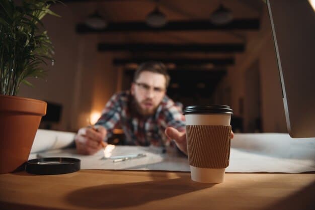 A person looking stressed at their desk, with an overflowing cup of coffee in the foreground, symbolizing the negative impact of excessive caffeine on stress levels.