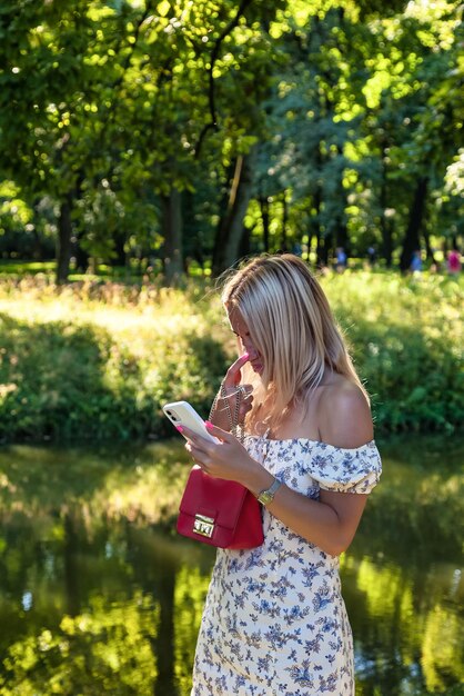 A person in a park, looking peaceful and relaxed, with their phone put away in their bag. The background shows lush greenery and other people enjoying outdoor activities.