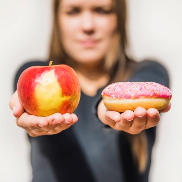 A person making a conscious decision to pick up an apple instead of a donut, symbolizing replacing a bad habit with a good one.