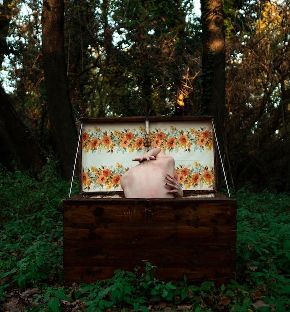 A person carefully placing a photograph into a wooden memory box, surrounded by other sentimental items. The scene evokes feelings of nostalgia and reflection.