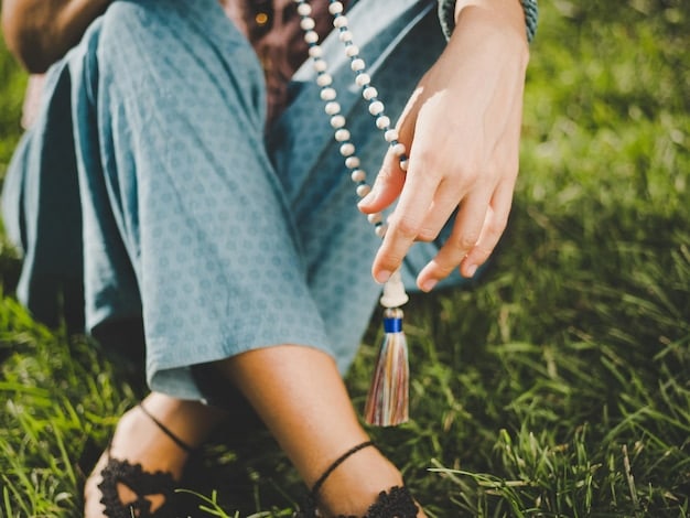 A close-up shot of hands gently holding prayer beads (mala beads) during meditation. The background is softly blurred, showing a peaceful meditation space with candles and plants, emphasizing mindfulness and spiritual practice.