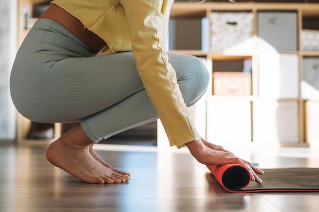 A close-up shot of a yogi's hands adjusting a yoga strap around their foot in a seated hamstring stretch.