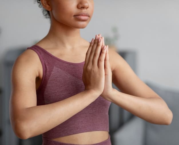 A close-up shot of an athlete's hands in a prayer position during a yoga session. The focus is on the hands and the athlete's calm expression. The background is blurred, suggesting a quiet and peaceful environment.