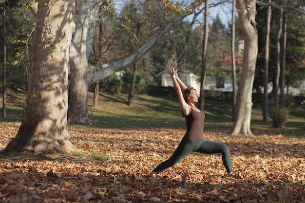 An athlete performing a perfect Warrior II pose on a yoga mat outdoors, showcasing strength and balance. The background is a natural setting with trees and soft sunlight.