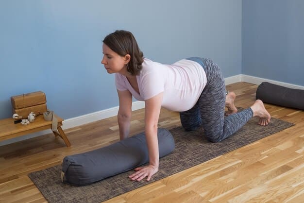 A pregnant woman in her third trimester sitting on a yoga bolster in a supported reclining position with her eyes closed and a serene expression. The room is softly lit, and the focus is on her relaxed posture.