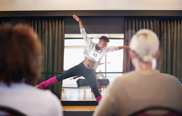 A dance therapy session in a brightly lit studio, with participants of various ages and backgrounds moving freely and expressively to music, guided by a therapist.