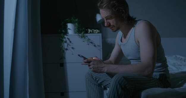 A person placing their phone on a nightstand in a darkened room, symbolizing disconnecting from technology.