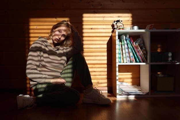 A person sitting alone, looking stressed and overwhelmed, with a hand resting on their forehead. The background is blurred, suggesting a sense of isolation and anxiety.