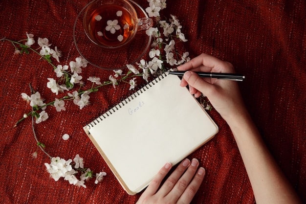 A close-up shot of a person's hands writing in a beautifully decorated journal with the words 