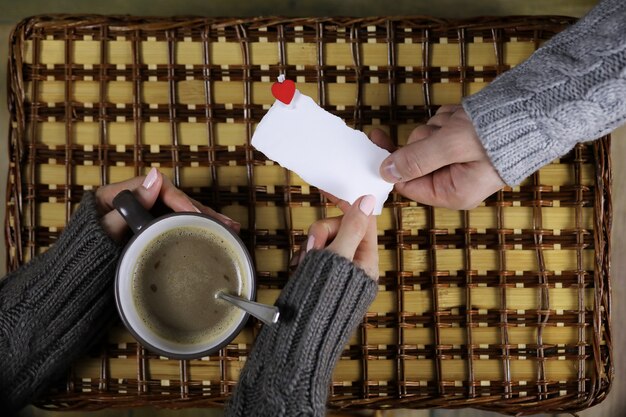 A person handing a thank-you card to another person. The card has a simple yet elegant design, and the setting is a cozy, warmly lit room, suggesting thoughtfulness and personal connection.
