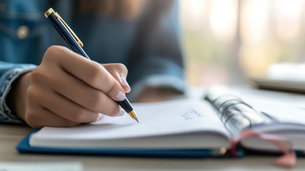 A close-up shot of a person writing in a journal, with a pen in hand. The journal is open to a page with headings like 