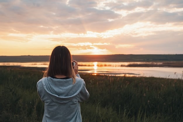 A person smiling while looking at a sunset. The image captures the beauty of nature and the feeling of gratitude for the simple things in life.