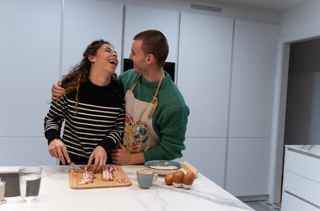 A couple laughing while cooking together in the kitchen, symbolizing shared experiences and intimacy.