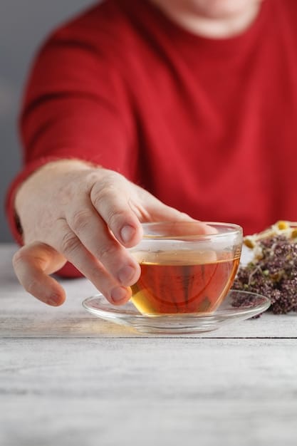 Close-up shot of a person’s hands holding a warm cup of herbal tea with a soft, blurred background of a cozy living room. The focus of the image emphasizes relaxation, comfort, and mindful moments of self-care.