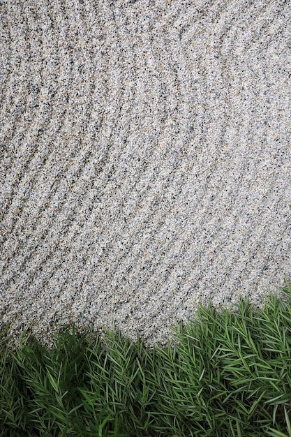 Close-up of a meticulously raked sand garden with distinct wave patterns. A few carefully placed rocks are visible, adding texture and form to the landscape.