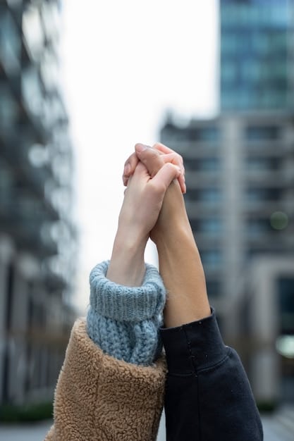 Close-up shot of two hands gently holding each other over a softly blurred background. Focus on the texture of the skin and the gentle connection between the hands, conveying tenderness and compassion.