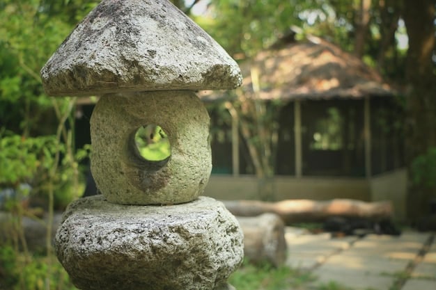 A close-up shot of a moss-covered stone lantern in a Japanese garden. The lantern is weathered and shows signs of age, with moss growing in the cracks and crevices. The background is blurred, emphasizing the lantern's texture and natural beauty.