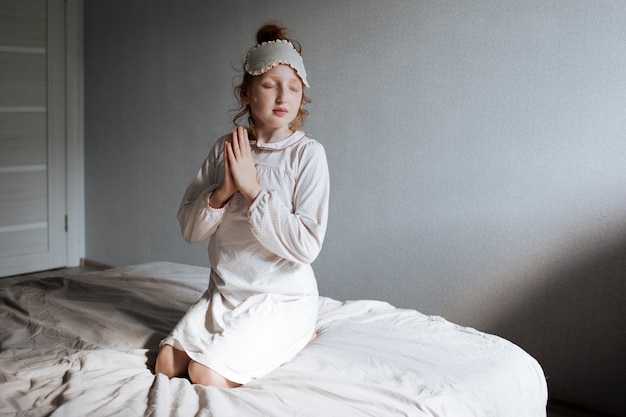 A person practicing mindful breathing in a dimly lit room before sleep. The focus is on their calm facial expression and relaxed posture, highlighting the serenity of the moment.