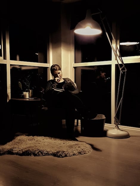 A person sitting in a dimly lit room, looking at old photos with a melancholic expression, symbolizing dwelling on the past.