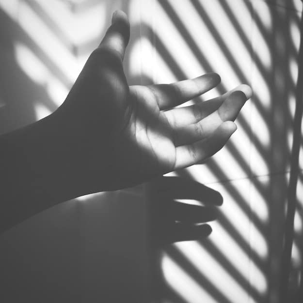 A close-up shot of hands gently placed in a meditation pose, with soft, diffused lighting creating a sense of calm and focus. The background is blurred, emphasizing the hands and the meditative gesture.