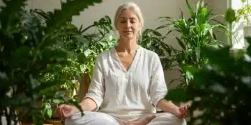 Serene person meditating in a sunlit room with green plants, cultivating mindful presence.