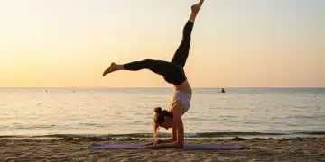 Yogi in forearm stand on beach at sunset, demonstrating advanced inversion mastery.