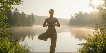 Woman in tree pose by a lake at sunrise