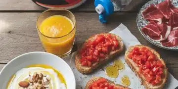 Desayuno español energético para deportistas, con tostadas, tomate, aceite y fruta fresca.