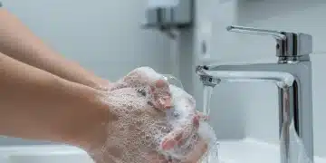Manos lavándose con jabón bajo el grifo, símbolo de higiene y prevención de enfermedades.